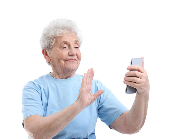 Starší žena s mobilním telefonem s selfie na bílém pozadí - Fotografie, Obrázek