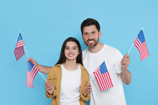 4 de julho - Dia da Independência dos EUA. Homem feliz e sua filha com bandeiras americanas em fundo azul claro - Foto, Imagem