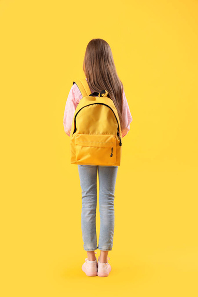 Niña con mochila sobre fondo amarillo, vista trasera - Foto, Imagen