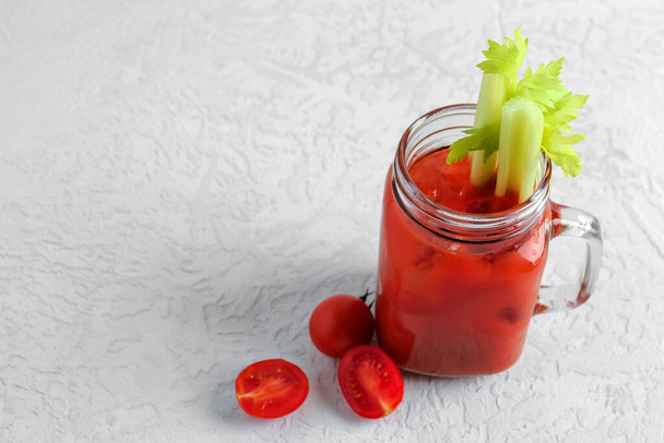 Mason jar of bloody mary with celery and tomatoes on white table - Photo, Image