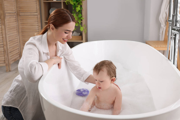 Mother washing her little baby in tub at home - Foto, imagen