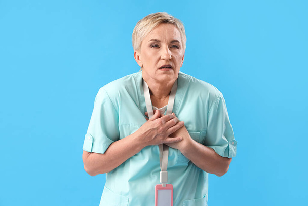 Medico femminile che ha un attacco di cuore su sfondo blu - Foto, immagini