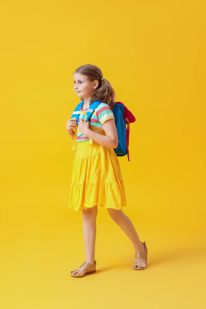 Cute little girl with backpack on yellow background - Photo, Image