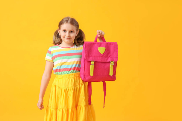 Schattig klein meisje met rugzak op gele achtergrond - Foto, afbeelding