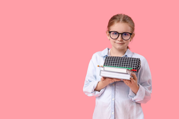 Kalem kutusu ve pembe arka plan kitapları olan küçük bir kız öğrenci. - Fotoğraf, Görsel