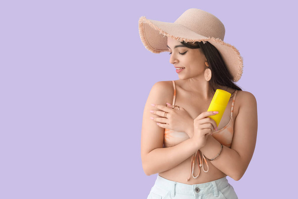Giovane donna con crema solare su sfondo lilla - Foto, immagini