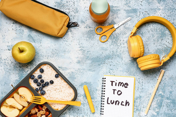 Cancelleria, cibo gustoso in scatola da pranzo e quaderno con testo TEMPO DI PRANZO su sfondo blu grunge - Foto, immagini
