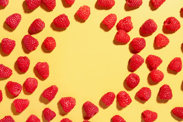 Frame made of fresh raspberries on yellow background - Fotó, kép