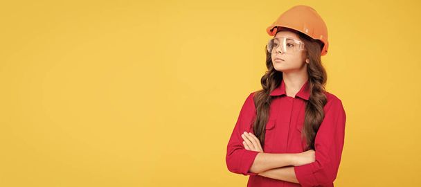 Renovation child, serious teenager girl in protective eyeglasses and helmet, copy space, building. Child builder in helmet horizontal poster design. Banner header, copy space - Fotó, kép