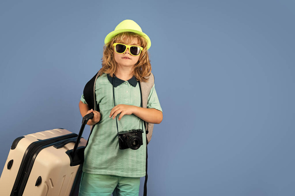 Stüdyo arka planında bavulu olan çocuk gezgin. Turist çocuk. Seyahat çantasıyla çocuk portresi. Seyahat, macera, tatil - Fotoğraf, Görsel