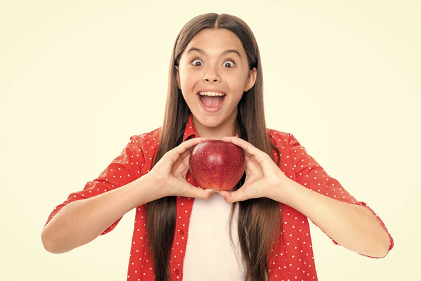 Dziewczynka je jabłko na białym tle. Tennager z owocami. Portret emocjonalnie zaskoczony podekscytowany nastolatek dziewczyna - Zdjęcie, obraz