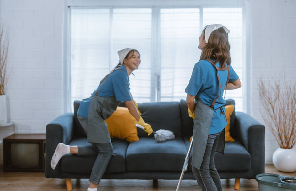 Enthusiastic house cleaning lady do various tasks with responsibility. Using mop, broom, laundry machine, cleaning supplies to wipe, scrub, and dust furniture, glassware, floors, clothes, dishes. - Фото, изображение