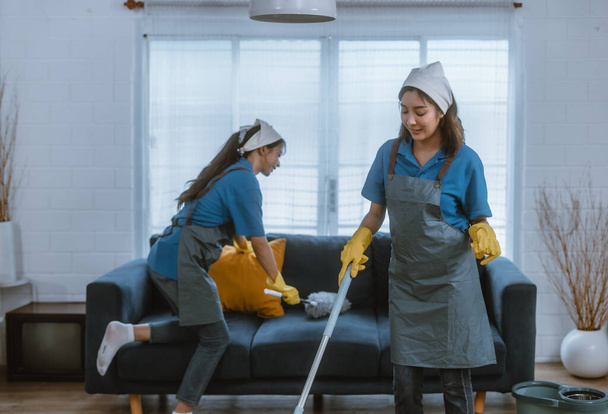 Enthusiastic house cleaning lady do various tasks with responsibility. Using mop, broom, laundry machine, cleaning supplies to wipe, scrub, and dust furniture, glassware, floors, clothes, dishes. - Фото, изображение