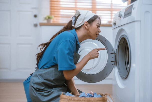 Энтузиастская уборщица дома выполняет различные задачи с ответственностью. Использование швабры, метлы, стиральная машина, чистящие средства, чтобы вытереть, скраб и пыль мебель, стекло, полы, одежда, посуда. - Фото, изображение