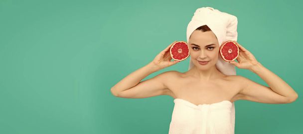 jeune femme en serviette après la douche avec pamplemousse sur fond bleu. vitamine c. Belle femme isolée visage portrait, bannière avec maquette espace de copie - Photo, image