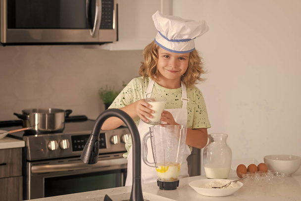Τα παιδιά μαγειρεύουν στην κουζίνα. Αστείος σεφ μαγειρεύει στην κουζίνα. Παιδί σεφ που φτιάχνει υγιεινό φαγητό. Πορτρέτο του μικρού παιδιού σε καπέλο σεφ - Φωτογραφία, εικόνα