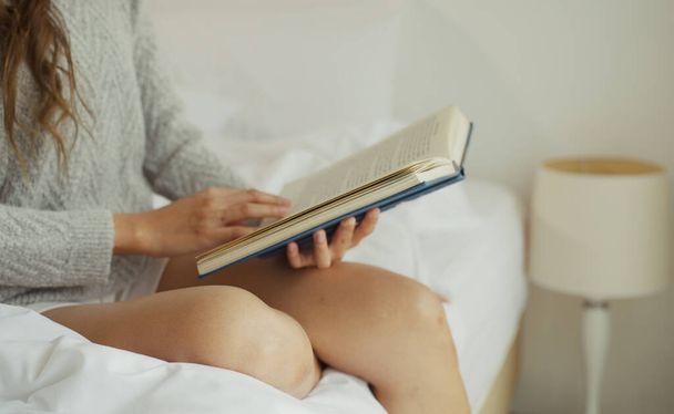 Jonge vrouw lezen boek op bed thuis. - Foto, afbeelding