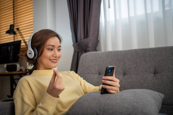 Woman wearing headphones and listening to music and singing happy at home on vacation. - Photo, Image