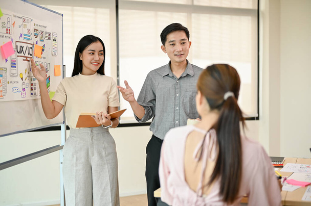 Dwóch profesjonalnych azjatyckich programistów prezentuje swój nowy projekt swojemu zespołowi podczas spotkania. startująca firma technologiczna, UI, UX - Zdjęcie, obraz