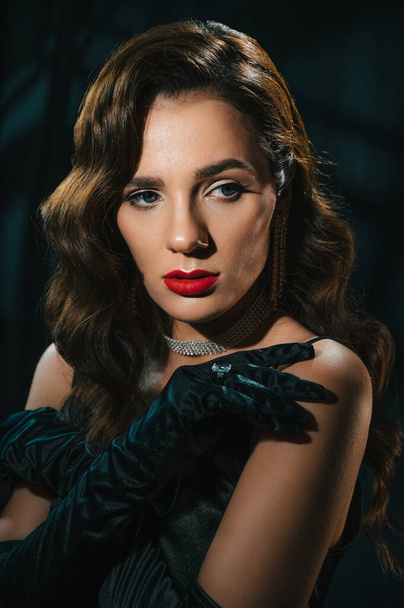 Portrait of brunette woman in classic retro style. Beautiful girl with a hairstyle and makeup with jewelry in vintage retro noir look. Concept of actress from a Hollywood film - Фото, изображение