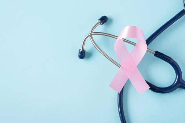 Różowa wstążka ze stetoskopem na niebieskim tle z przestrzenią do kopiowania, miesiąc świadomości raka piersi - Zdjęcie, obraz