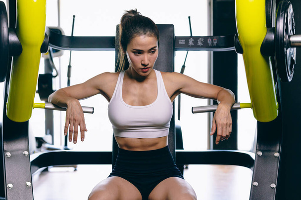 Güzel bir Asyalı kadın spor modeli sağlıklı ince eğitim spor spor spor salonunda ağırlık makinesiyle kas yapar. - Fotoğraf, Görsel