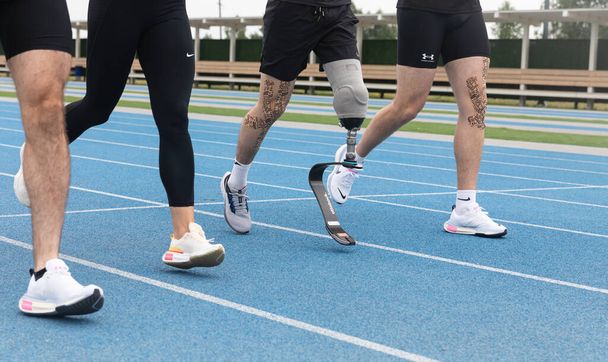 KYIV, UKRAINE - липень. 55, 2023: Спортсмен з протезною ногою бачить біг у групі на біговій доріжці на стадіоні - Фото, зображення