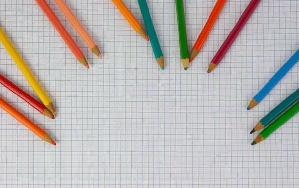 Colored pencils for back to school placed in a notebook, the pencils are drooping at the top of the image leaving a hole for copy - Foto, immagini