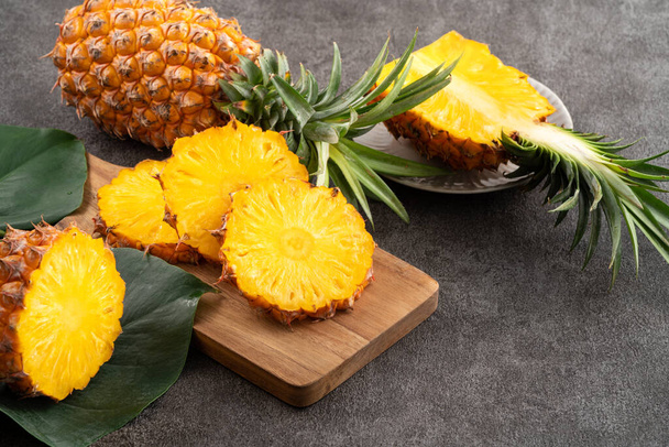 Fresh cut sliced juicy pineapple in a plate over dark gray table background. - Fotó, kép