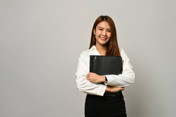 Attraktive asiatische Sekretärin, Büroleiterin, die über grauem Hintergrund steht. - Foto, Bild