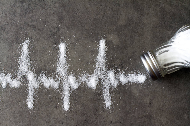 Salt shaker, cardiogram made of salt, hypertension concept  - Фото, изображение