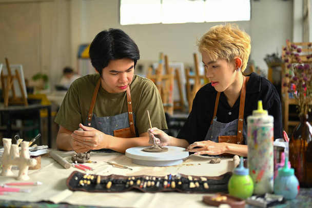 Image of happy gay man couple enjoying creative process, creating handmade ceramics in art class. - Zdjęcie, obraz