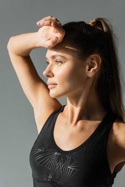 Portrét sportovkyně v moderní sportovní podprsenka odvrací pohled na šedý, aktivní životní styl - Fotografie, Obrázek