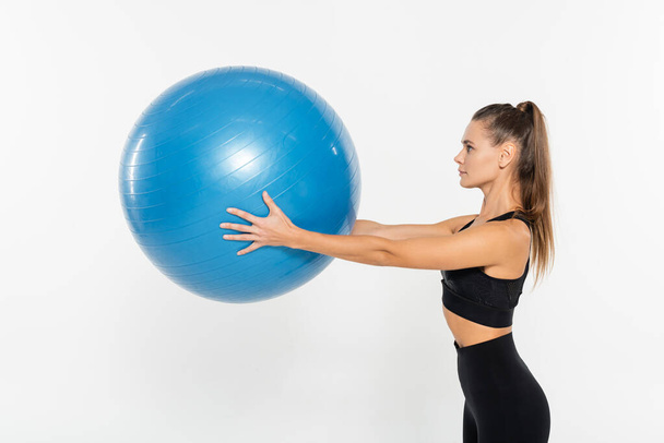mujer en forma de desgaste activo sosteniendo pelota de fitness aislado en blanco, concepto de mujer atlética - Foto, Imagen
