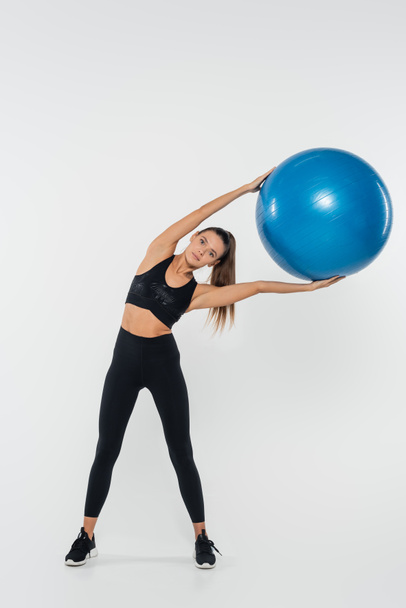 mujer haciendo ejercicio con bola de estabilidad y de pie sobre fondo blanco, concepto saludable y en forma - Foto, Imagen