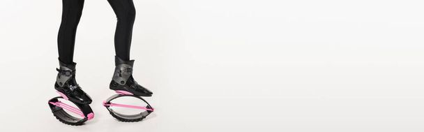 zábava cvičení, oříznutý záběr ženy v kangoo skákání boty na bílém, vyvážení a odrazit, banner  - Fotografie, Obrázek