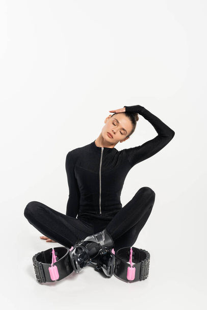 μπότες για άλματα, αθλητική γυναίκα κάθεται με σταυρωμένα πόδια, kangoo jumping παπούτσια, μυϊκή χαλάρωση - Φωτογραφία, εικόνα