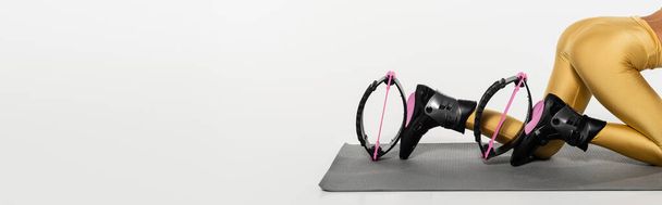 vista recortada de la mujer en el ejercicio de desgaste activo en la estera de fitness en zapatos de salto de kangoo, bandera  - Foto, imagen
