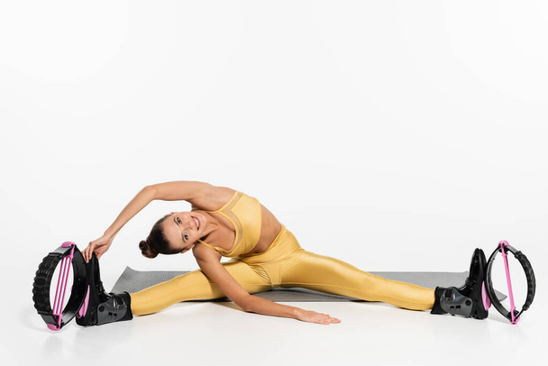 ευέλικτη γυναίκα σε ενεργό φθορά άσκηση σε fitness mat, kangoo jumping παπούτσια, τονισμένο σώμα, αθλητισμός  - Φωτογραφία, εικόνα