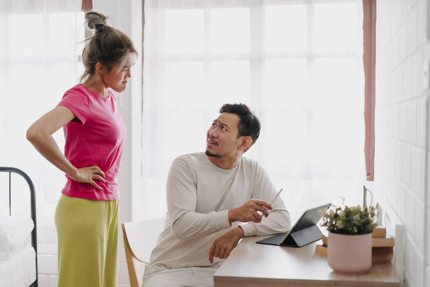 Asian wife asking husband to stop working and watching with computer tablet. - Foto, imagen