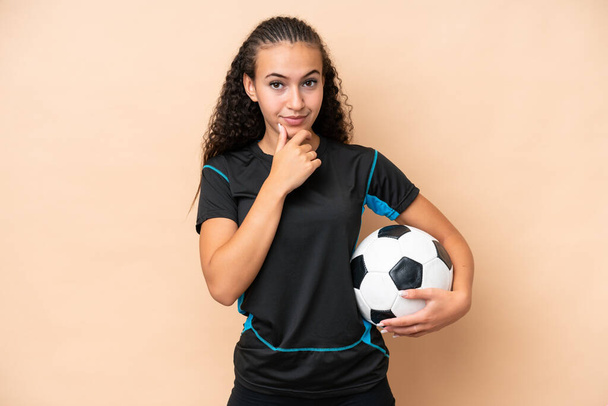 młody piłkarz kobieta odizolowany na beżowy tło myślenie - Zdjęcie, obraz
