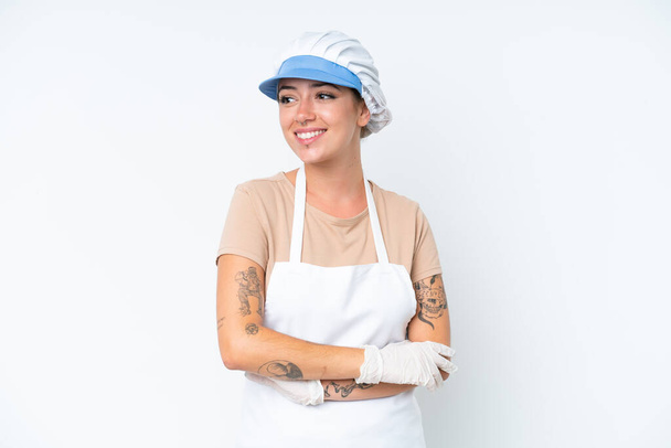 Fishmonger wearing an apron and holding a raw fish isolated on white background looking to the side and smiling - Foto, imagen