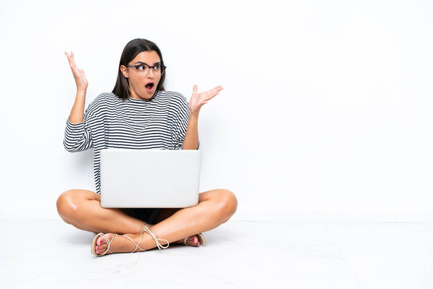 Young caucasian woman with a laptop sitting on the floor with surprise facial expression - Foto, afbeelding