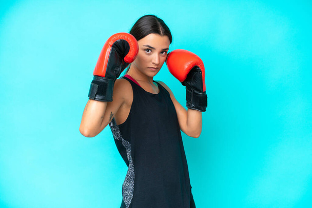 Young caucasian woman isolated on blue background with boxing gloves - Фото, зображення