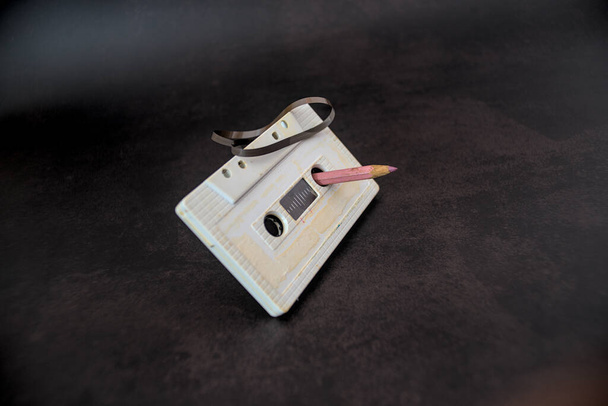 Cassette vintage avec un crayon pour rembobiner sur fond sombre - Photo, image