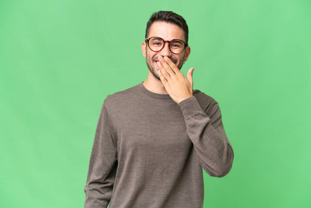 Young handsome caucasian man over isolated background happy and smiling covering mouth with hand - Photo, Image