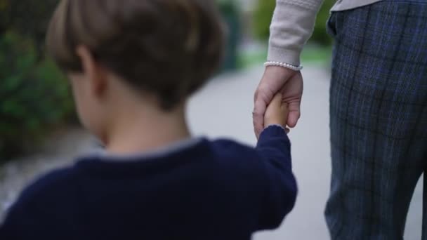 Parent holds the hand of a little child. Trust family concept. Mother holding hands with son walking together outdoors in motion - Footage, Video