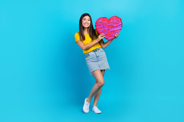 Full size photo of young japanese lady hold pink paper postcard gift valentine day pink heart romance isolated on blue color background. - 写真・画像
