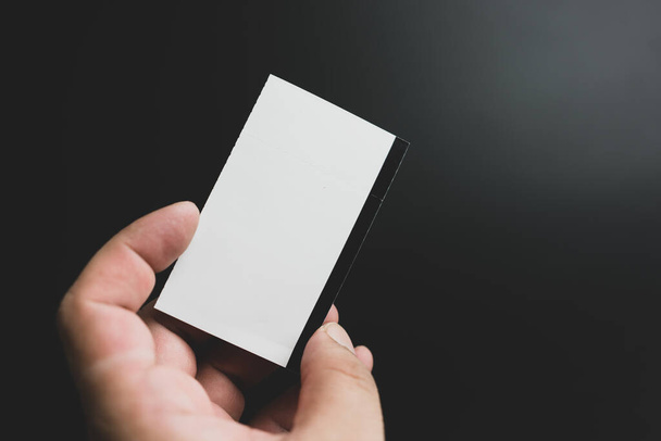 Man keep paper ticket blank mockup on a black background. - Foto, Imagen