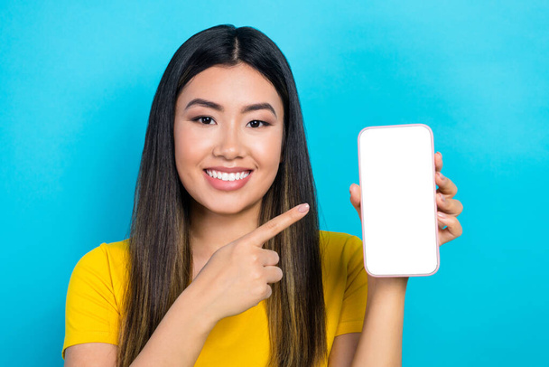 Portrait of young vietnamese lady directing finger web proposition offer sale discount insurance phone screen isolated over blue background. - Fotoğraf, Görsel